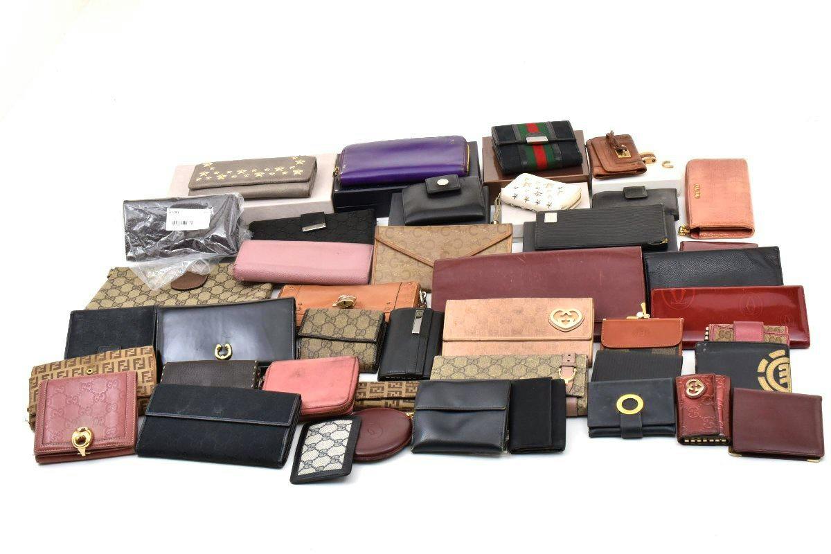 A large assortment of wallets and small leather goods arranged on a white background.
