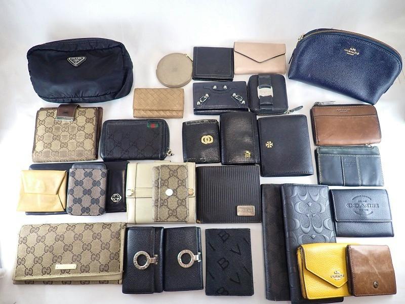 Multiple wallets and coin cases (assorted designer brands) arranged flat on a white background.