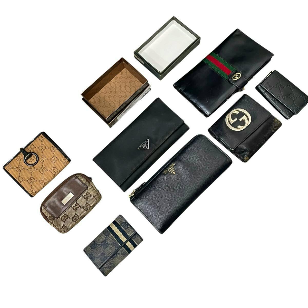 Several branded wallets and small leather goods (Prada and Gucci) arranged on a white background.