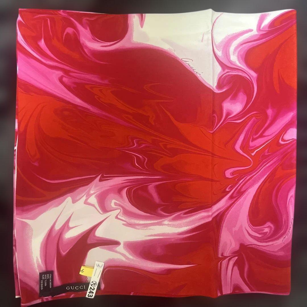 Rectangular red-and-white marble patterned Gucci scarf laid flat with the brand tag visible.