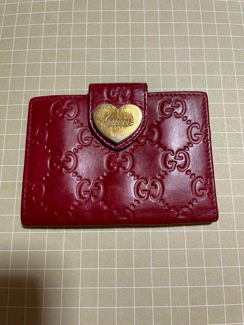 Red Gucci key case with embossed GG pattern and a gold heart-shaped logo snap.