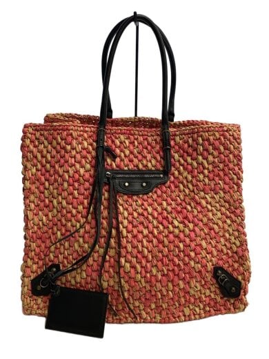 A red woven reusable tote bag with black handles and black leather trim photographed against a white background.
