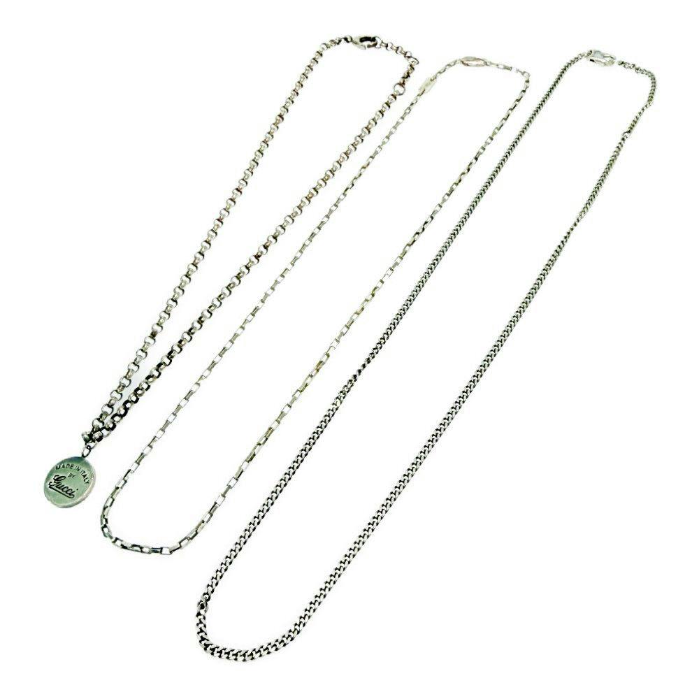 Three silver Gucci necklaces laid flat on a white background, one with a round logo pendant.