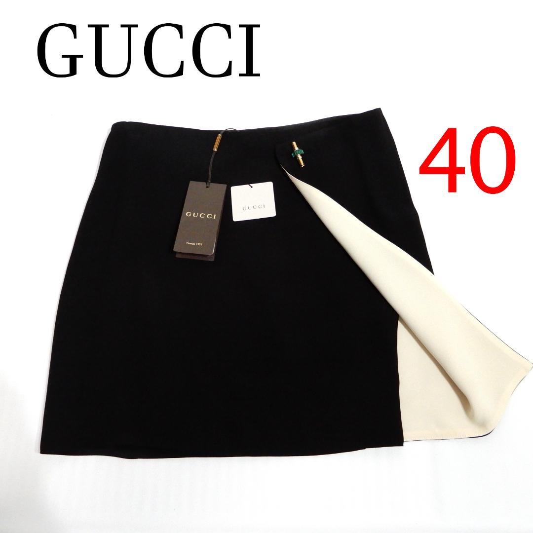 Flat-lay photo of a black Gucci mini skirt (size 40) with tags and a cream inner lining partially turned back.