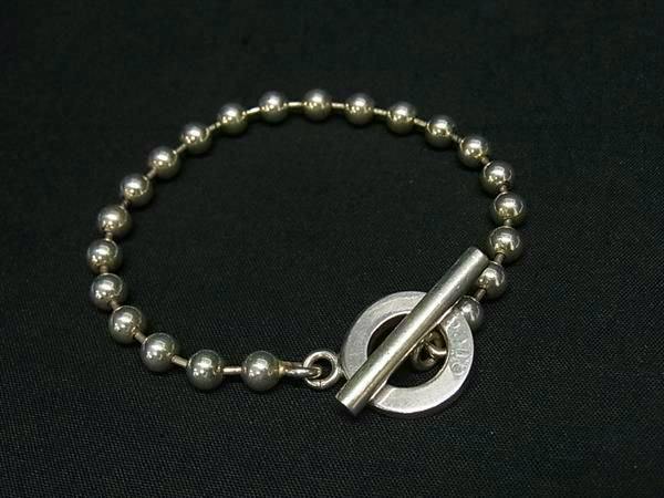 Silver beaded GUCCI SV925 bracelet with a circular toggle clasp on a black background.