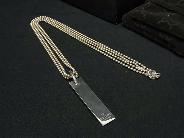 GUCCI SV925 rectangular logo plate pendant necklace with beaded chain laid on a black background.