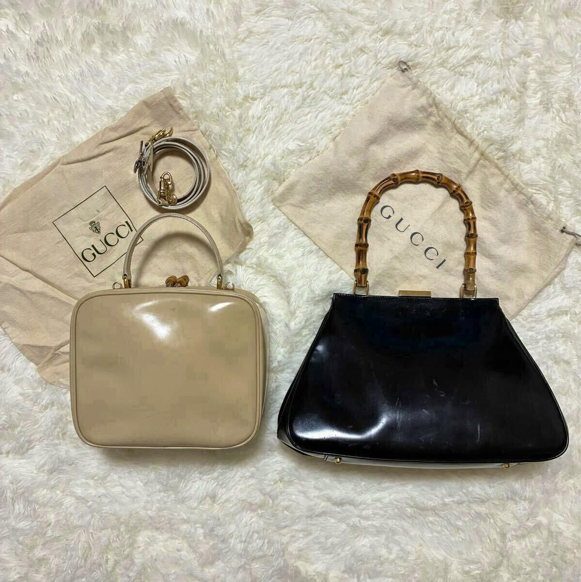 Two Gucci women's handbags—a beige boxy vanity bag and a black bag with a bamboo handle—shown with Gucci dust bags and a detachable strap on a white fur surface.