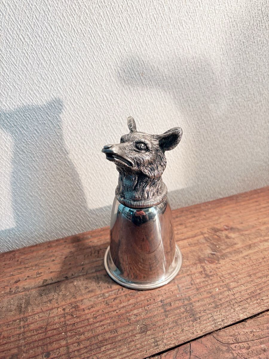 Ornamental iron goblet/shot glass with a fox head (GUCCI animal shot glass) placed on a wooden surface.