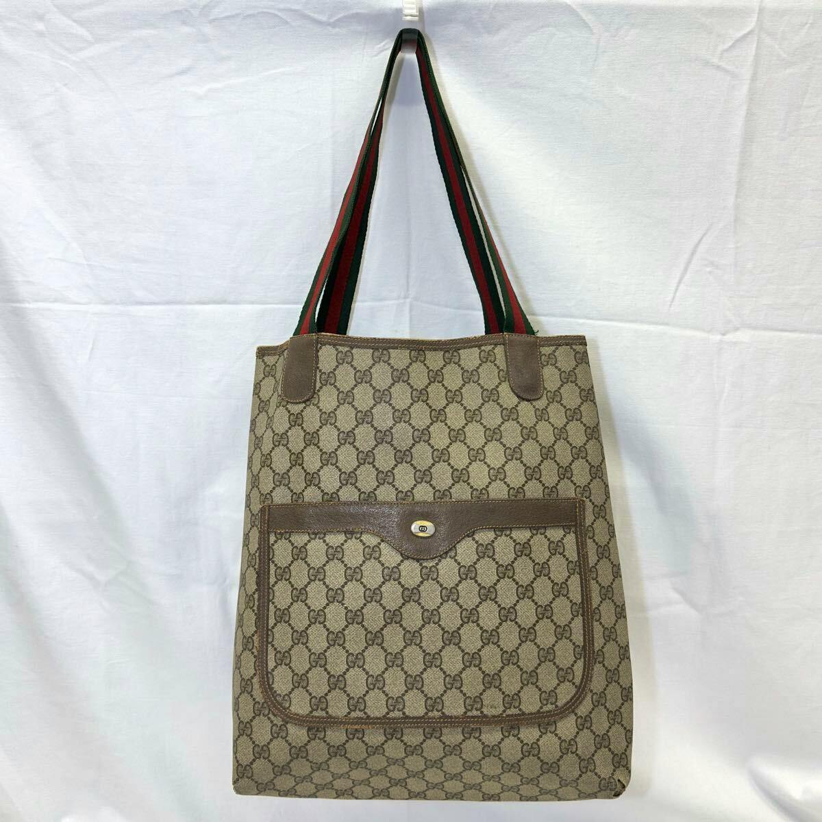 Front view of a Gucci GG-pattern canvas tote bag with green-red-green webbed shoulder straps and an exterior front pocket.