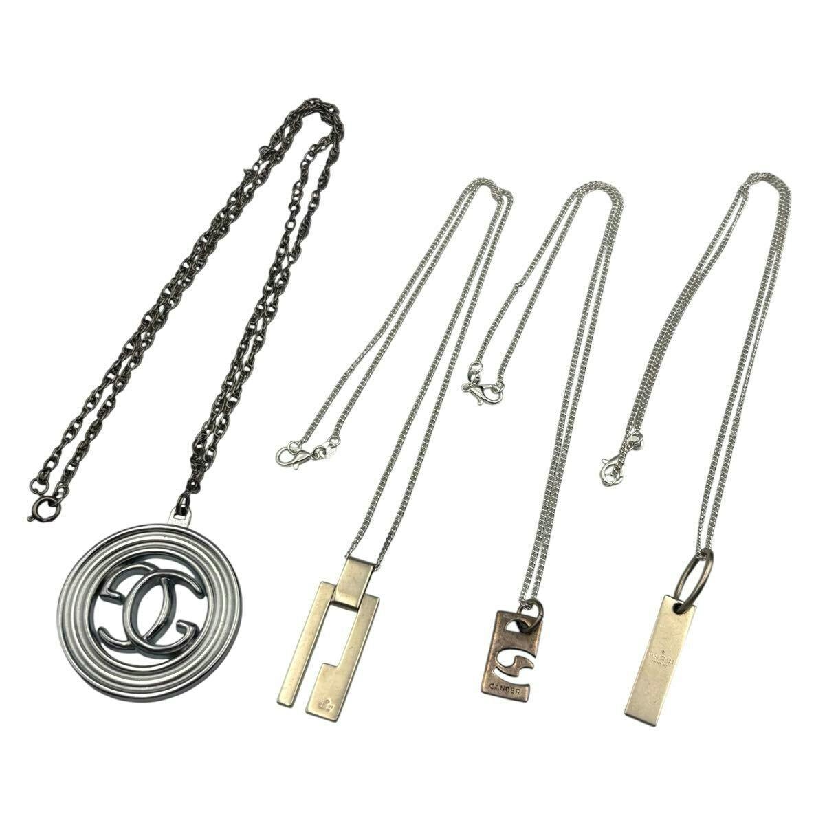 Four silver Gucci necklaces laid flat on a white background, including a round pendant with an interlocking G logo and three bar-style pendants.