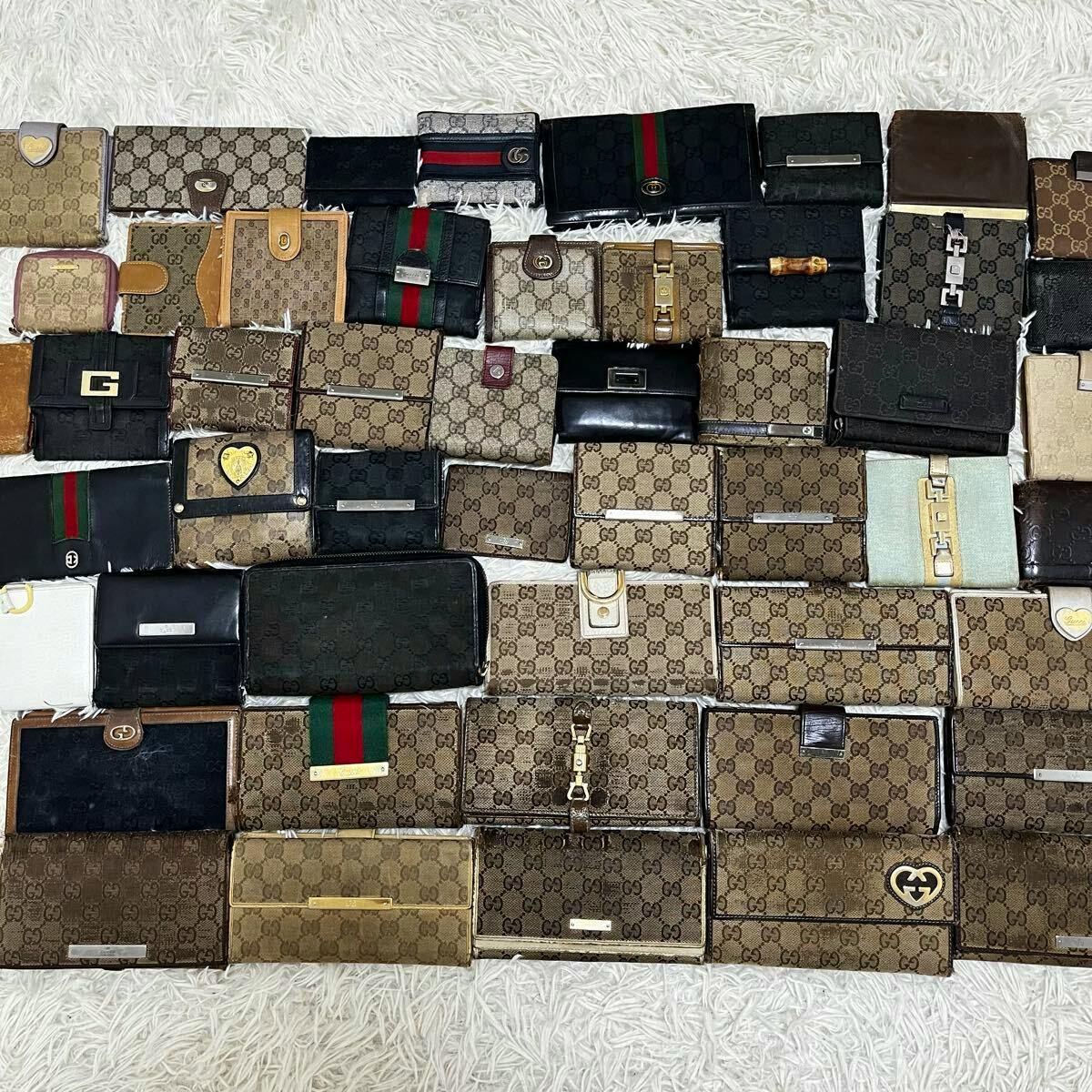 Multiple GUCCI canvas wallets and coin cases with GG monogram patterns arranged on a white rug.