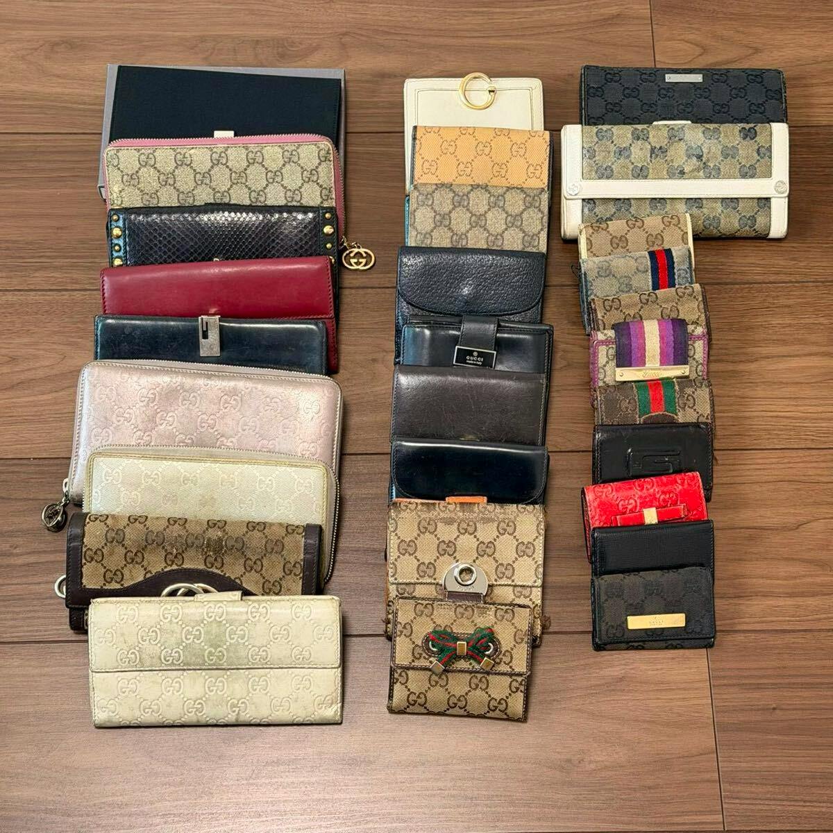 Assorted GUCCI wallets and small leather cases arranged in rows on a wooden floor.