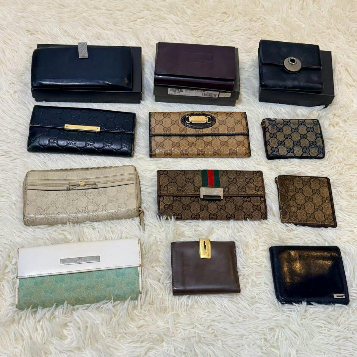 Twelve GUCCI wallets and key cases from a bulk set arranged on a white shag rug.