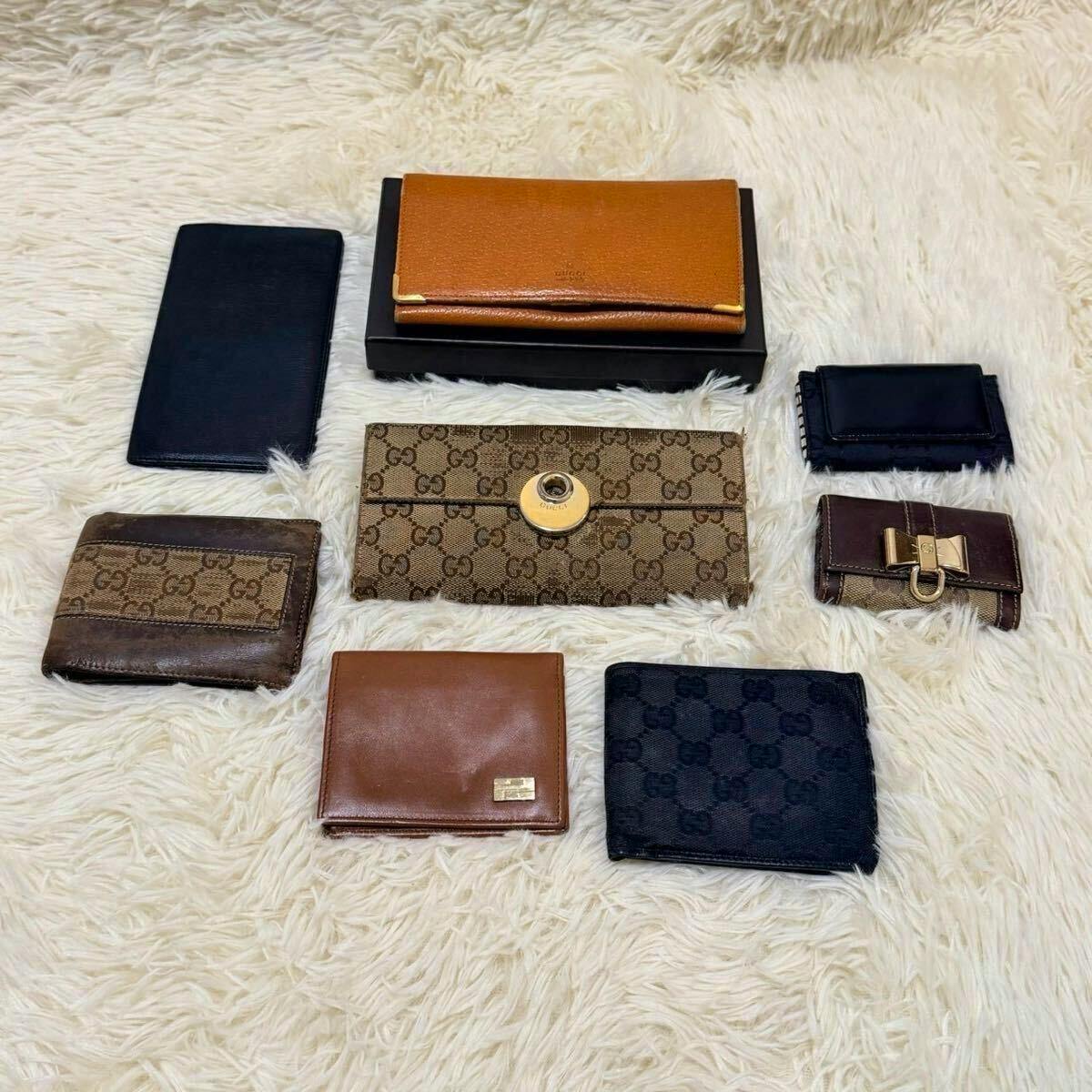 Eight Gucci wallets and key cases arranged on a white fur surface.