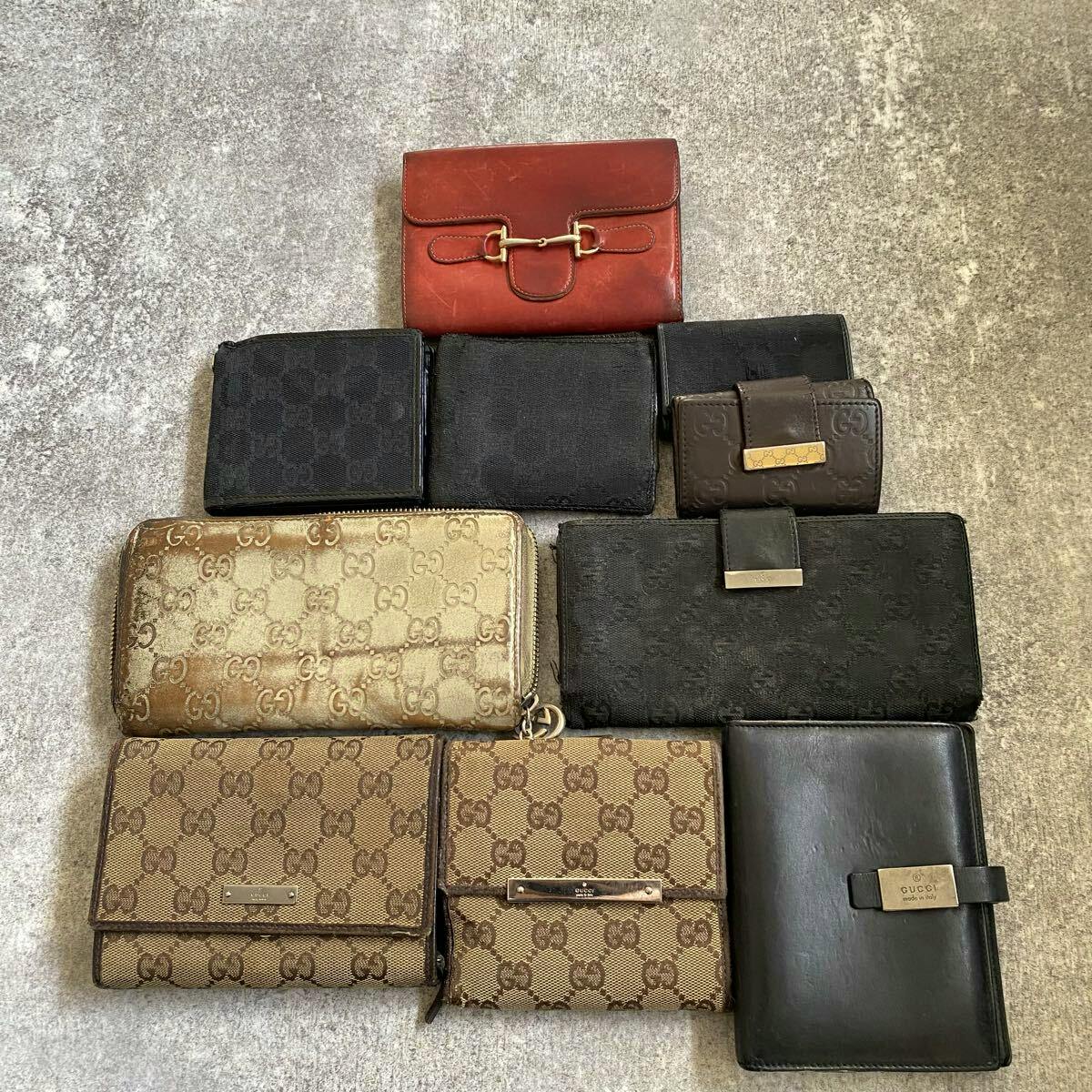 Ten used Gucci wallets in various GG canvas and leather styles arranged flat on a surface.