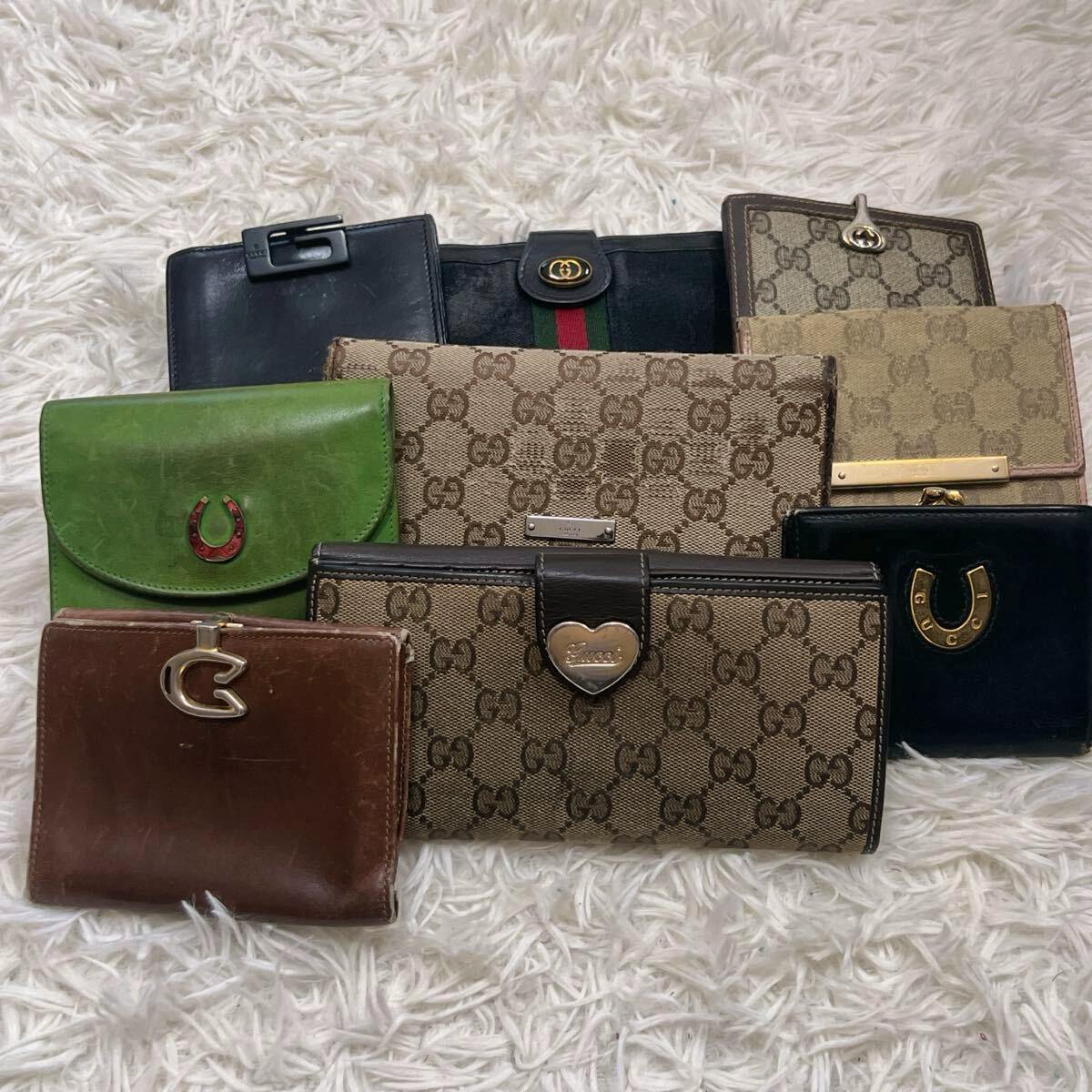 A group of Gucci wallets in GG canvas and leather arranged on a white rug.