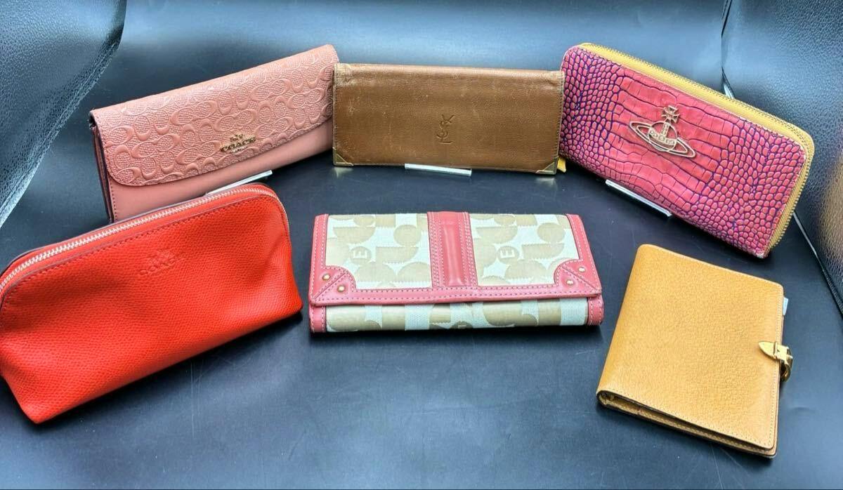 Several wallets and pouches from a bulk set, including a pink Vivienne Westwood zip-around wallet with an orb logo, arranged on a black surface.