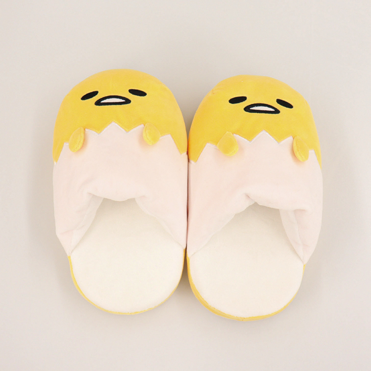Top-down photo of a pair of ぐでたまクニャック slippers showing yellow character faces and cracked-egg shell design.