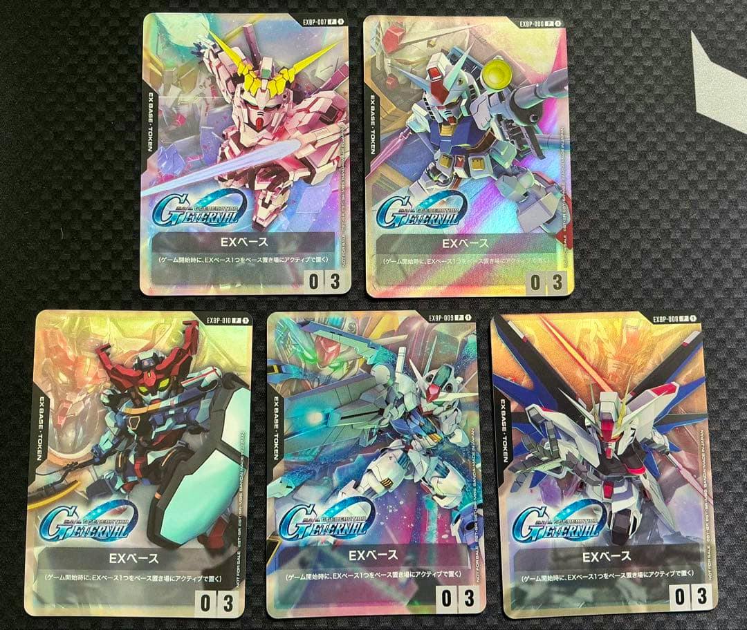 Five Gundam Card Game EXベース promo trading cards laid out face-up showing holographic mecha artwork.