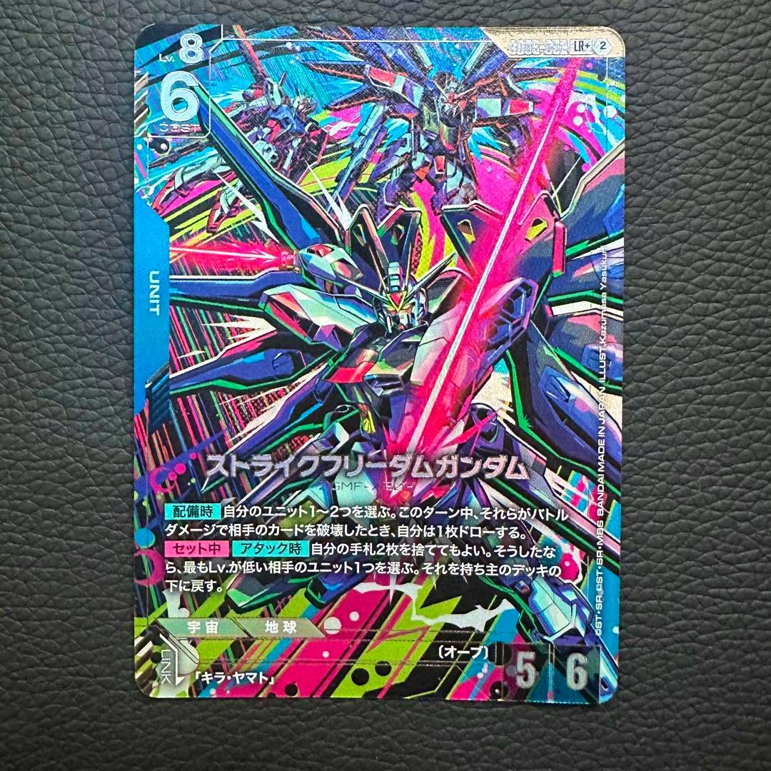 Front photograph of the Strike Freedom Gundam trading card showing colorful artwork and Japanese text on a dark textured background.