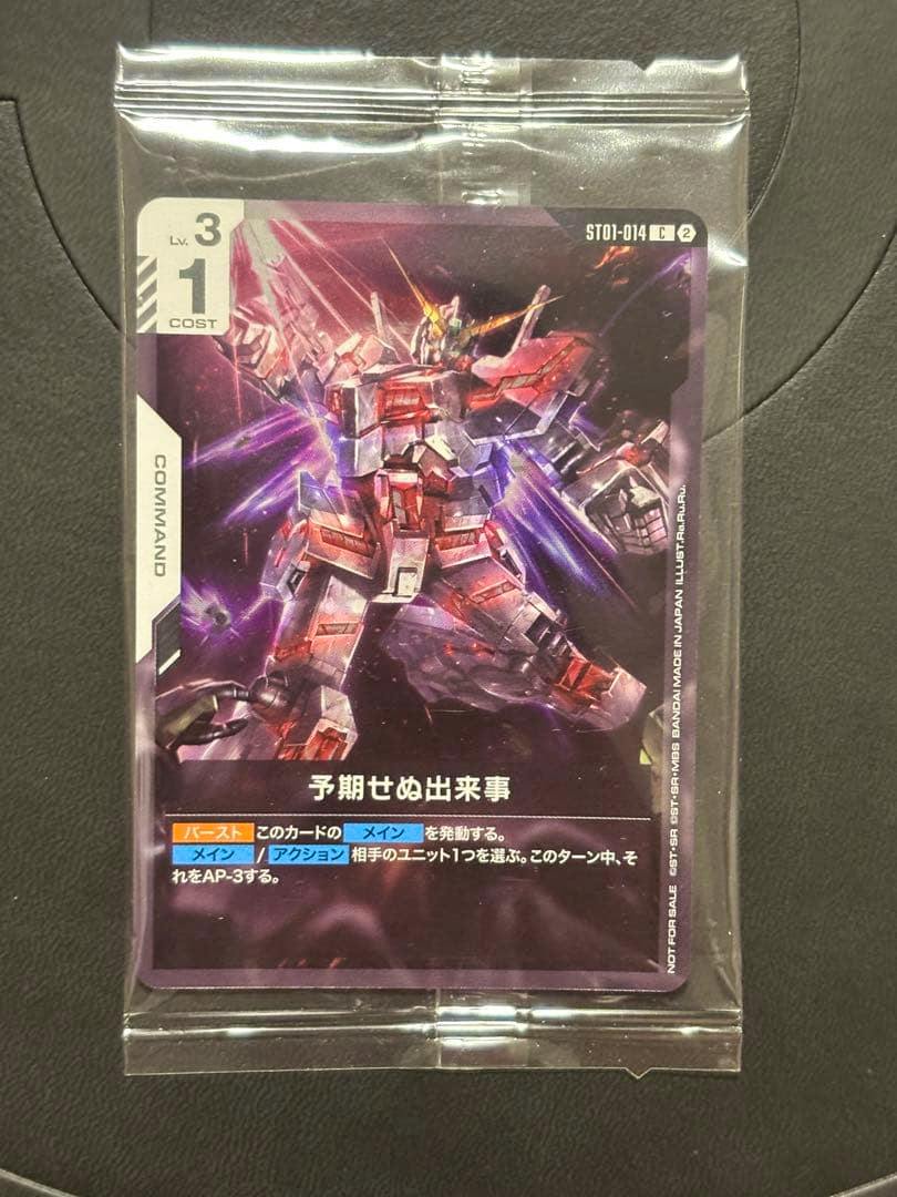Trading card '予期せぬ出来事' (Gundam promo) showing a Unicorn Gundam illustration inside a clear plastic sleeve on a black background.