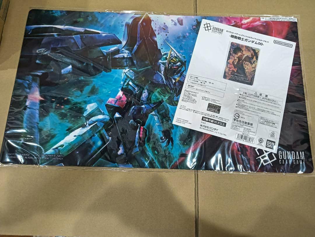Official Gundam Card Game playmat showing Mobile Suit Gundam 00 artwork with an attached product information sheet.