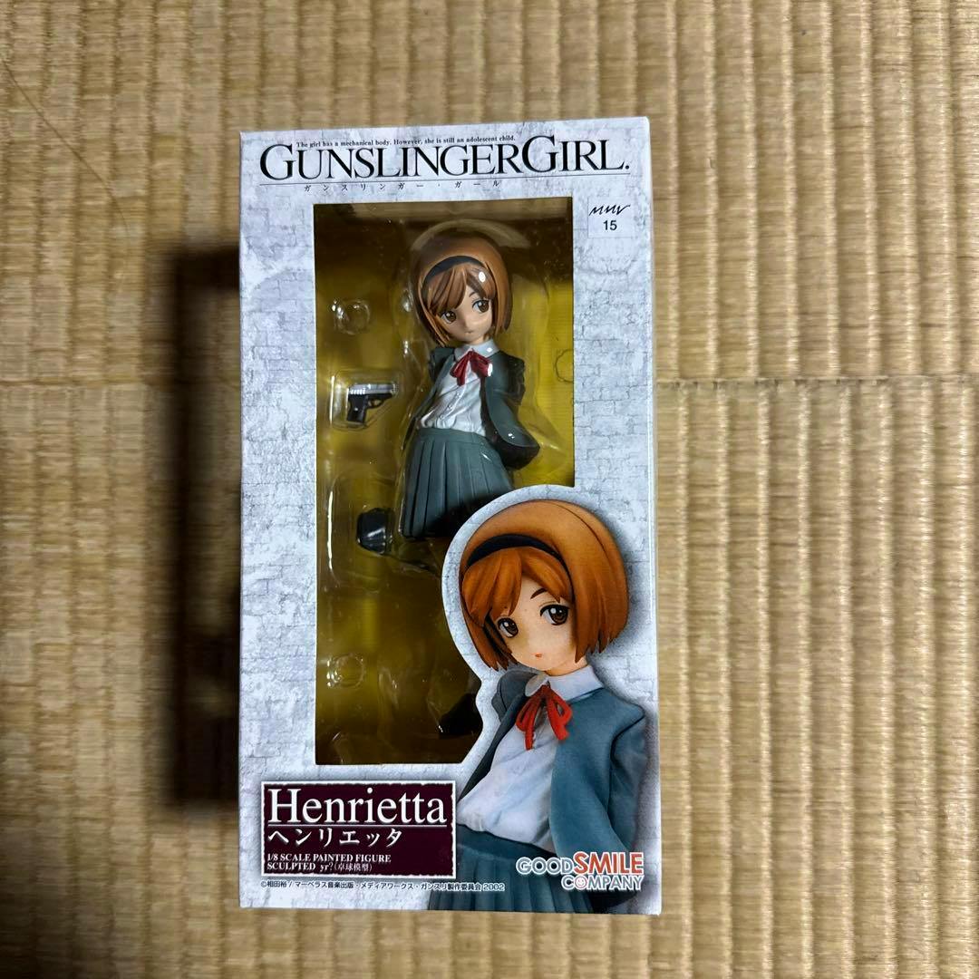 Front view of the unopened boxed Gunslinger Girl Henrietta 1/8 figure visible through the window, with box artwork and Good Smile Company logo.