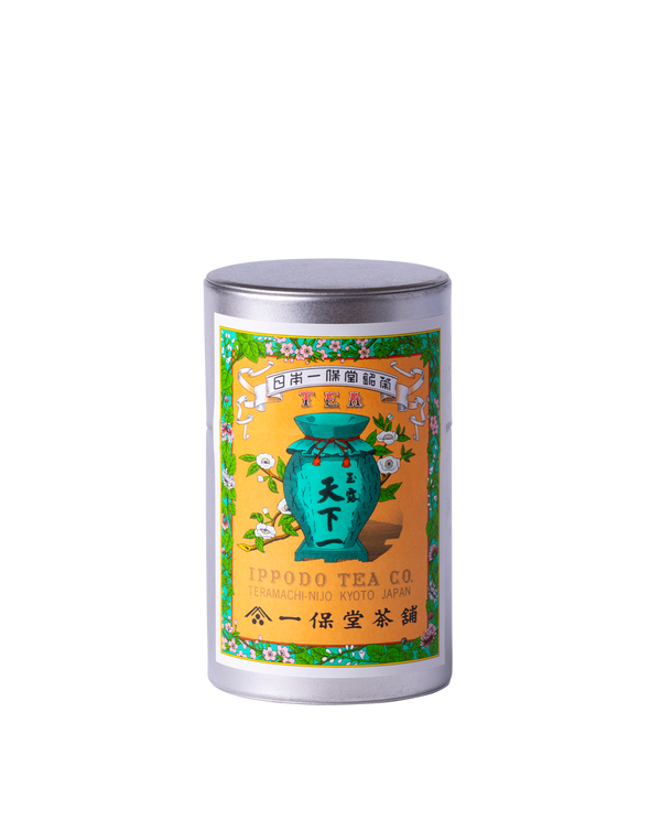 A cylindrical metal tea tin with a colorful label showing a green jar and Japanese text on a black background.