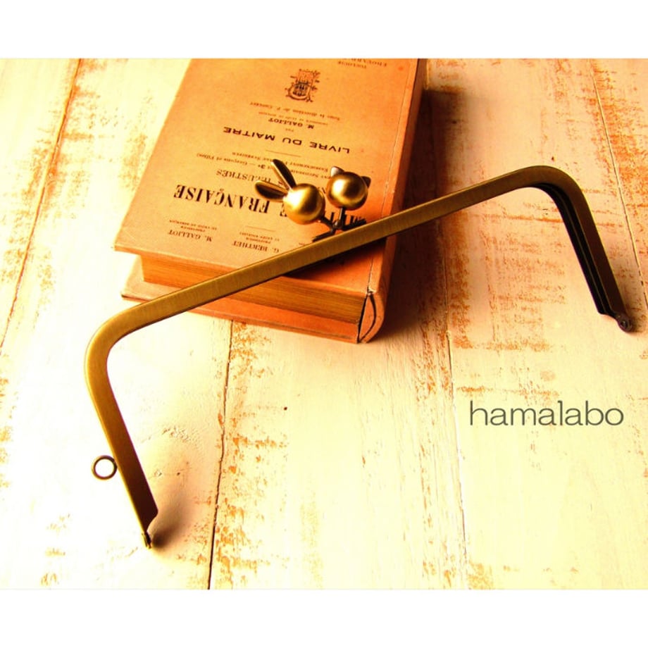 Antique-gold 24cm rectangular metal clasp frame with rabbit and cat ball knobs photographed on a wooden surface.
