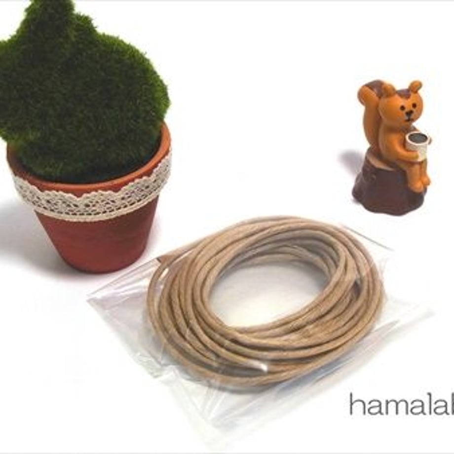 Coiled paper twine (HA-515, No.20, 5-meter roll) in a clear plastic bag beside a small potted plant and a bear figurine.