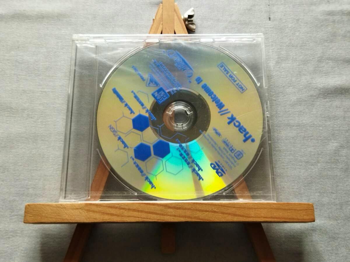 Front view of the .hack//Welcome to “THE WORLD” promotional DVD disc in a clear plastic case showing blue printed text and hexagon graphics.