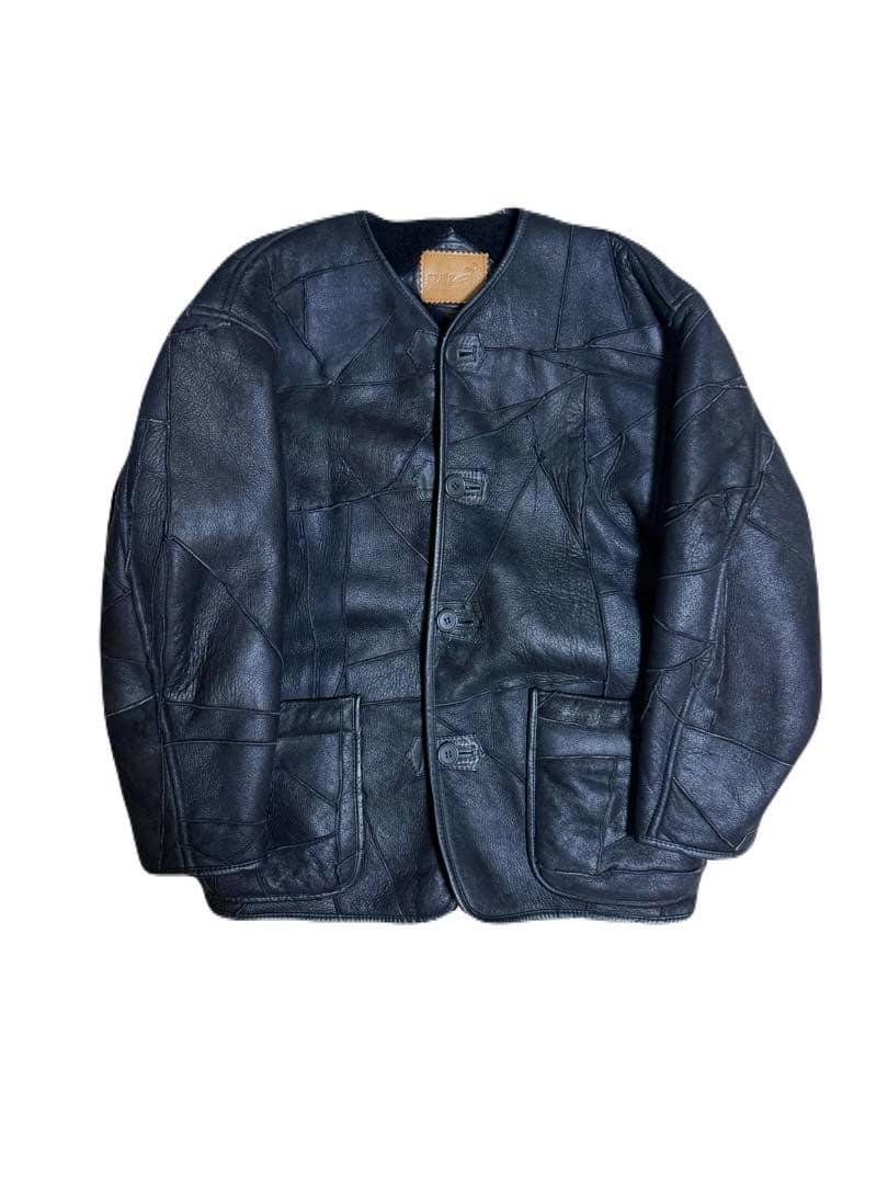 Black leather mouton jacket with front buttons and two patch pockets laid flat on a white background.