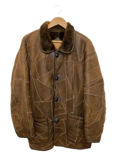 Front view of a brown lambskin jacket with a fur collar and patchwork stitching hanging on a wooden hanger.