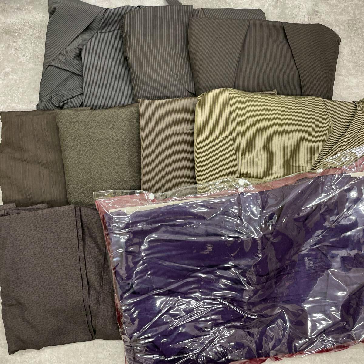 Folded hakama pieces in various striped and solid fabrics with a purple garment in a clear plastic bag visible.