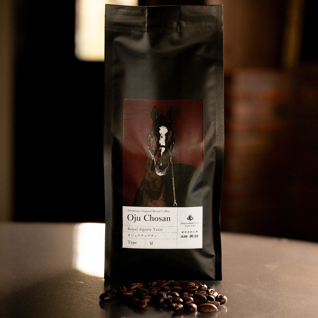 A black bag of Oju Chosan roasted coffee beans with a horse label, with roasted coffee beans in front.