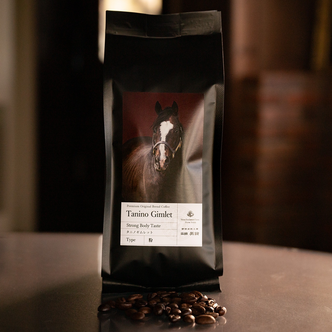 A black bag of roasted coffee beans labeled “Tanino Gimlet” with a horse image on the label and a small pile of coffee beans in front.