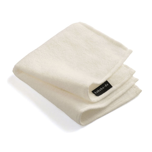 Folded white cotton hand towel with a small black brand tag visible.