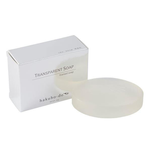 A round transparent bar of soap shown next to its white box packaging labeled "TRANSPARENT SOAP".