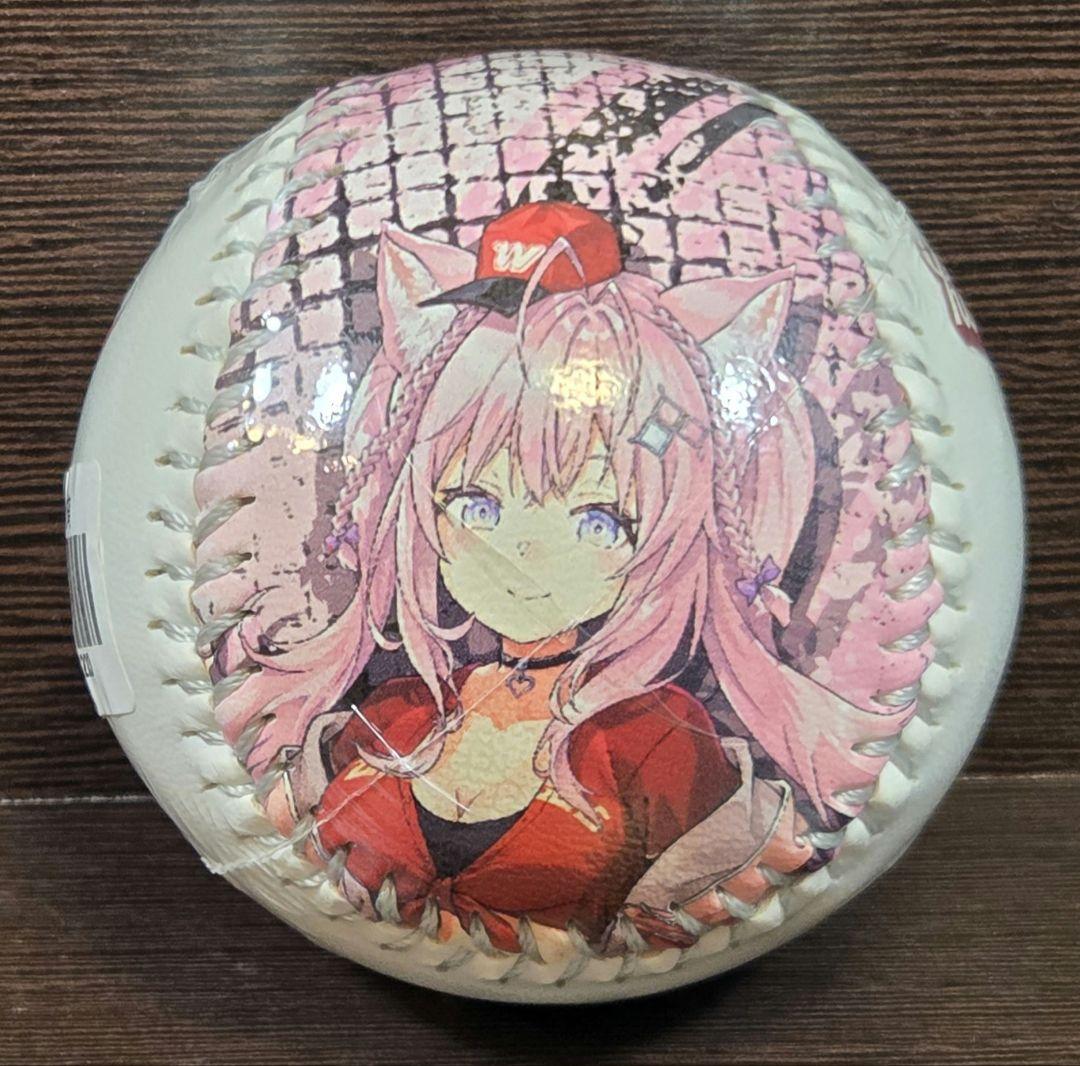 Baseball with a printed illustration of Hakui Koyori, a pink-haired anime girl in a red outfit, on a wooden surface.
