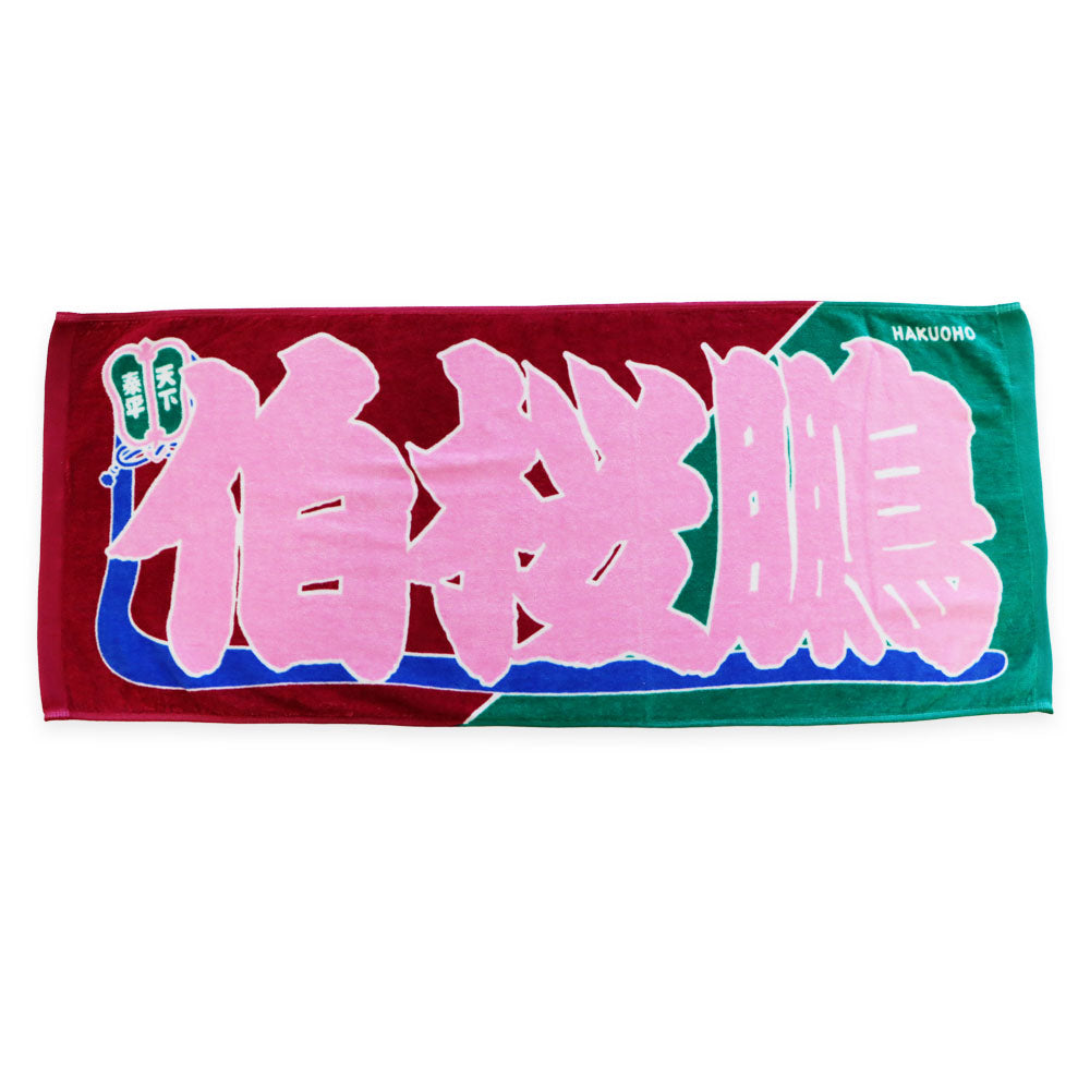 A rectangular towel showing large pink Japanese characters on a red and green background.