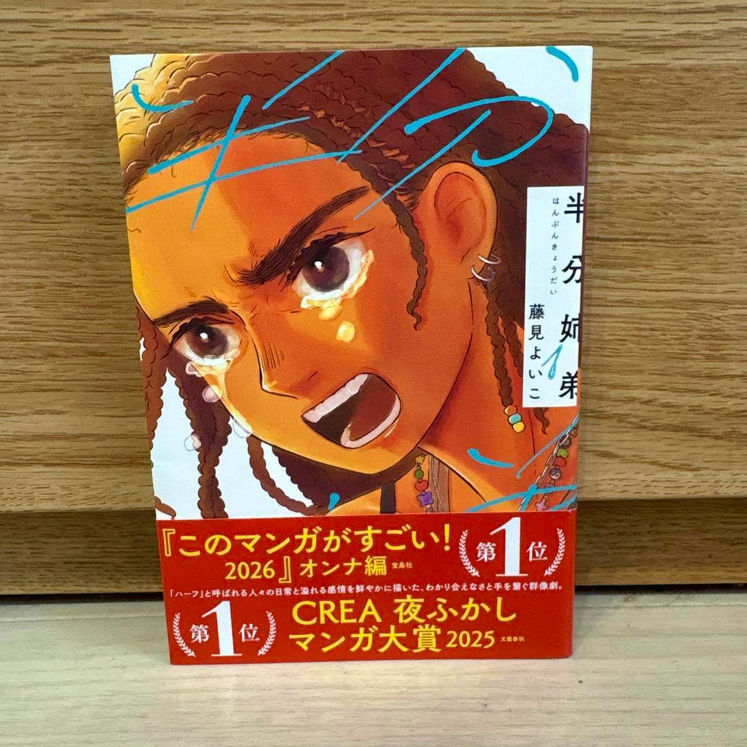 Front cover photo of the comic book 半分姉弟 showing an illustrated crying face and a red promotional band with Japanese text.