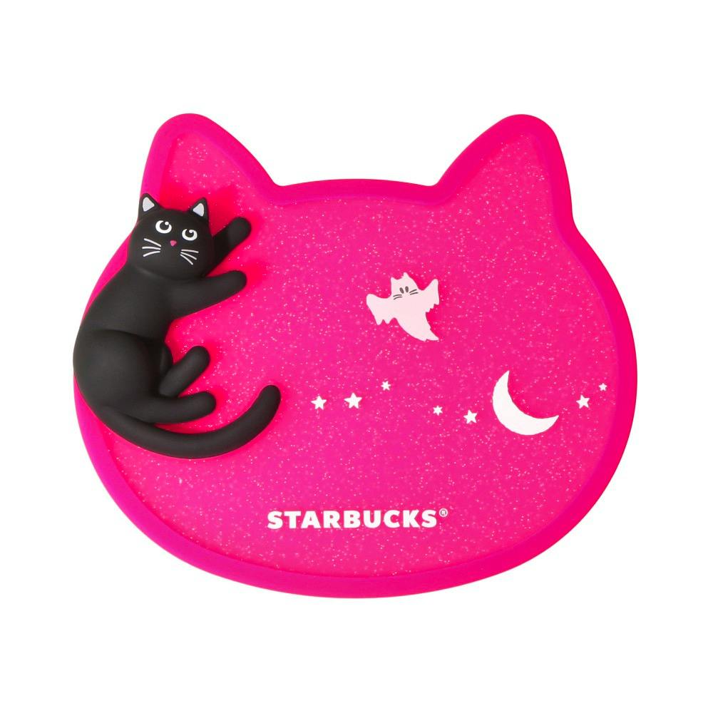 Pink cat-shaped rubber coaster showing a raised black cat figure, small moon and ghost graphics, and the word "STARBUCKS".
