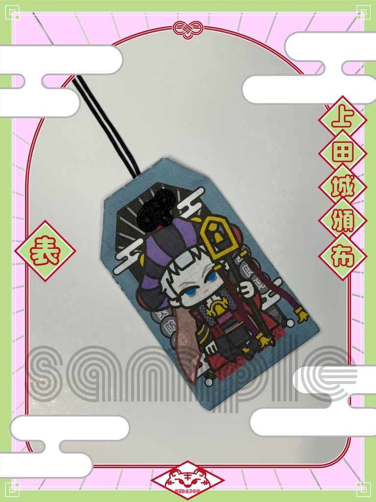 Front side of the cloth amulet showing a Halloween-themed cartoon character design with attached black cord.