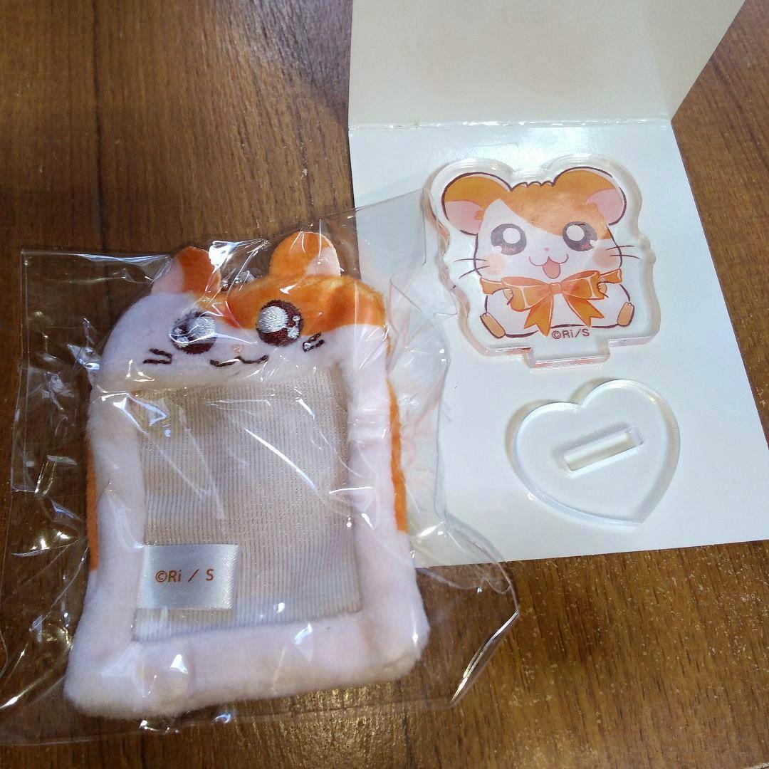 Packaged Hamtaro plush mini photo holder shown beside an acrylic stand on a wooden surface.