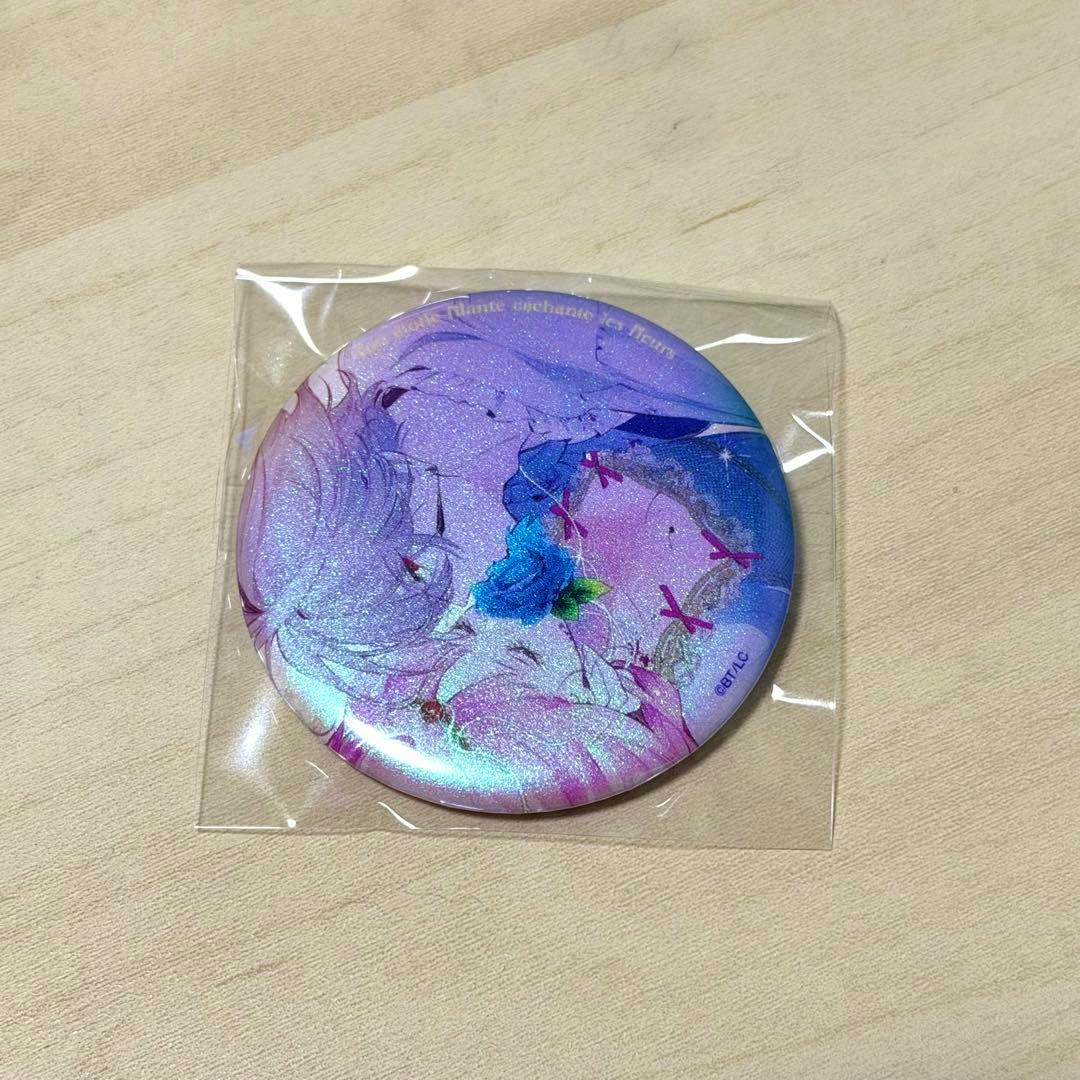 A round aurora-effect can badge with an illustrated character in pink and purple tones inside a clear plastic sleeve on a light wood surface.