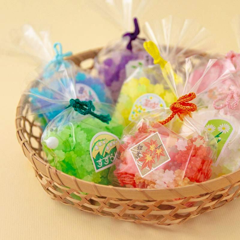 A basket containing several small clear bags of colorful packaged sugar candy.