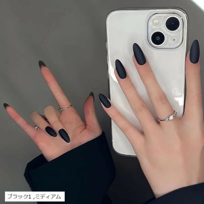 Hands wearing matte black almond-shaped nail tips holding a smartphone.