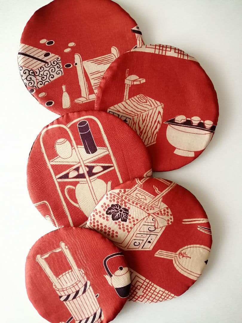 Four round handmade polyester coasters with a red printed pattern arranged on a white background.