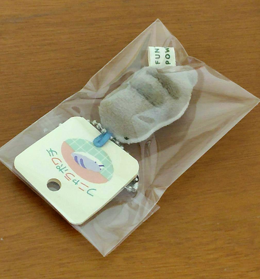A small handmade Tsuchinoko plush keychain in a clear plastic bag with its product tag attached.