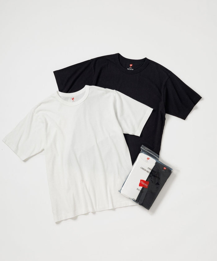 Flat-lay of a white and a black Hanes washed cotton crew neck T-shirt with a packaged two-pack beside them.